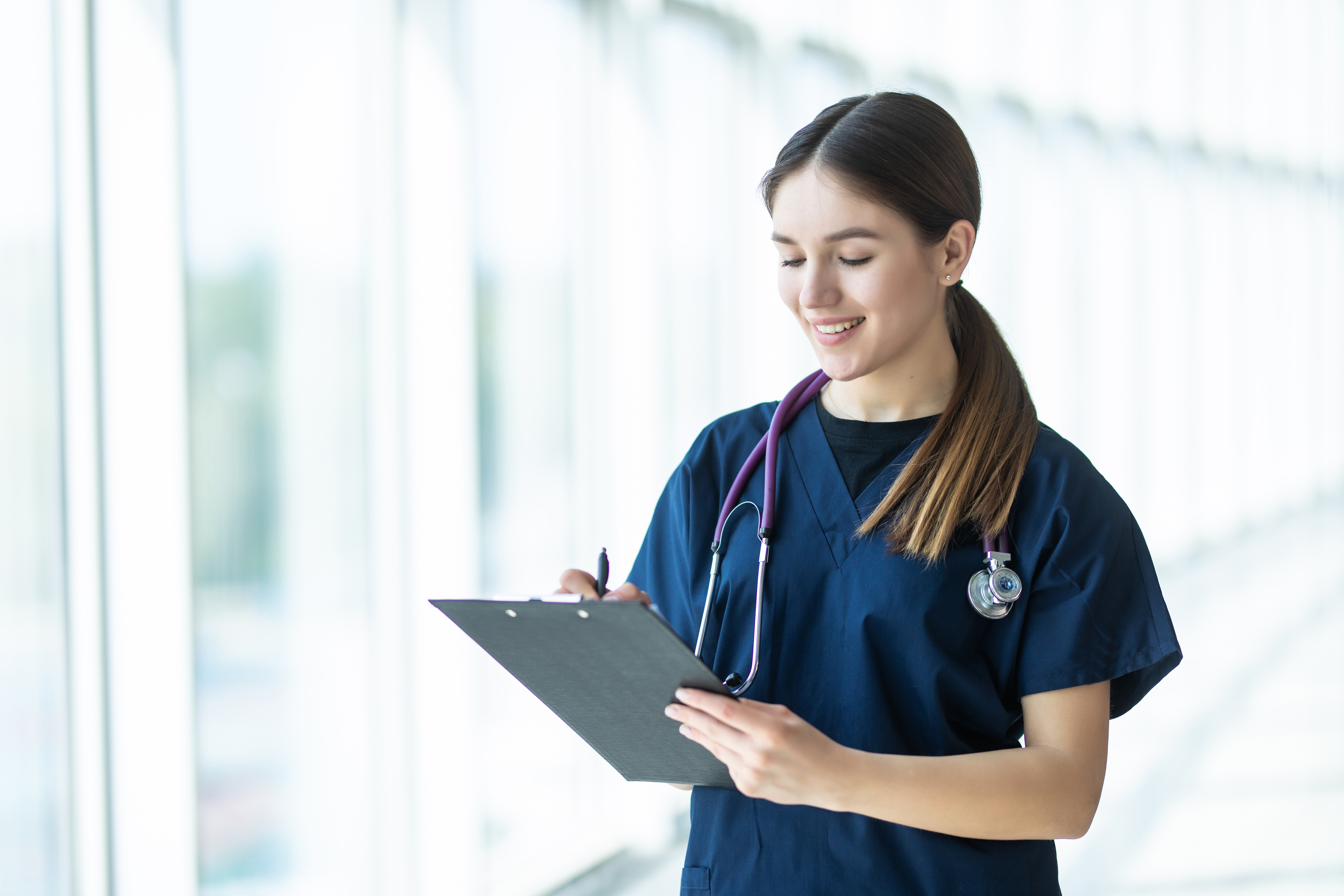 Smiling young female doctor holding a clipboard, healthcare concept