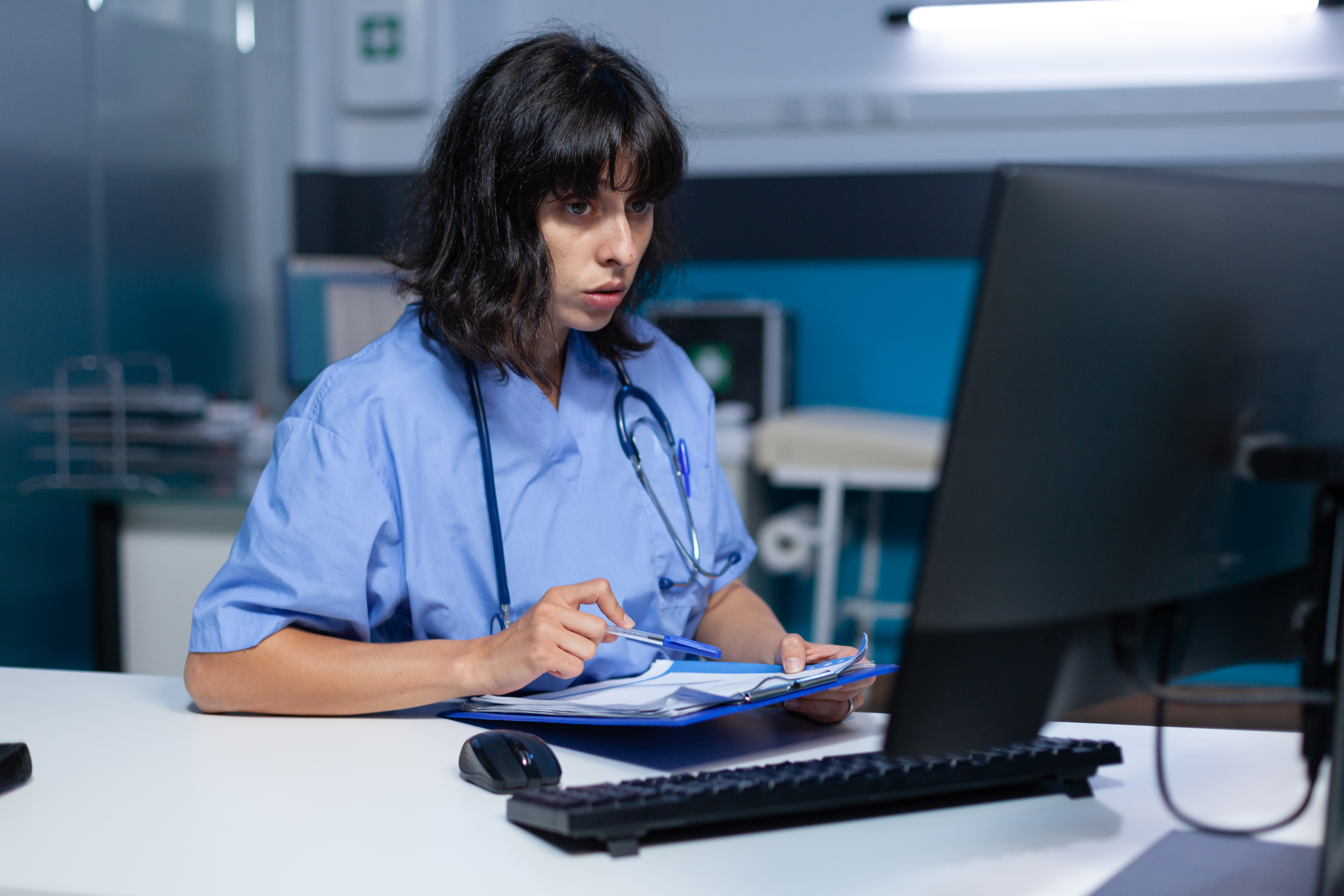 Medical assistant analyzing documents and files on monitor